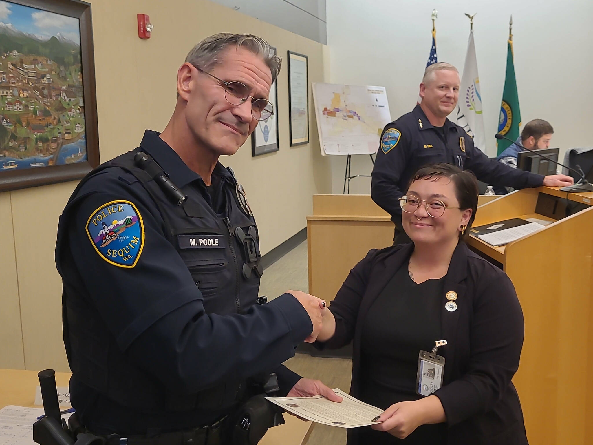 Deputy Mayor Rachel Anderson thanks Sequim police officer Mark Poole with a proclamation of his Lifesaving Award on Oct. 14 for preventing a man from jumping from the River Road bypass in August. (John Southard)