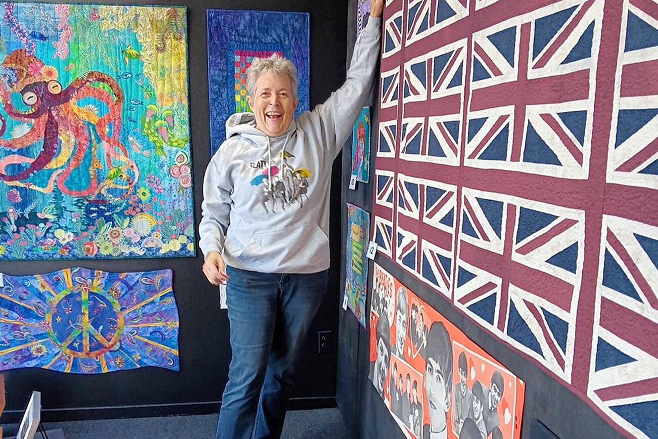 Port Angeles textile artist Merrie Jo Schroeder, installing the “Beatlemania” walk-by exhibit at 675 Tyler St., Port Townsend. The display of Beatles memorabilia and Beatles-themed art quilts and textile pieces will continue through November.