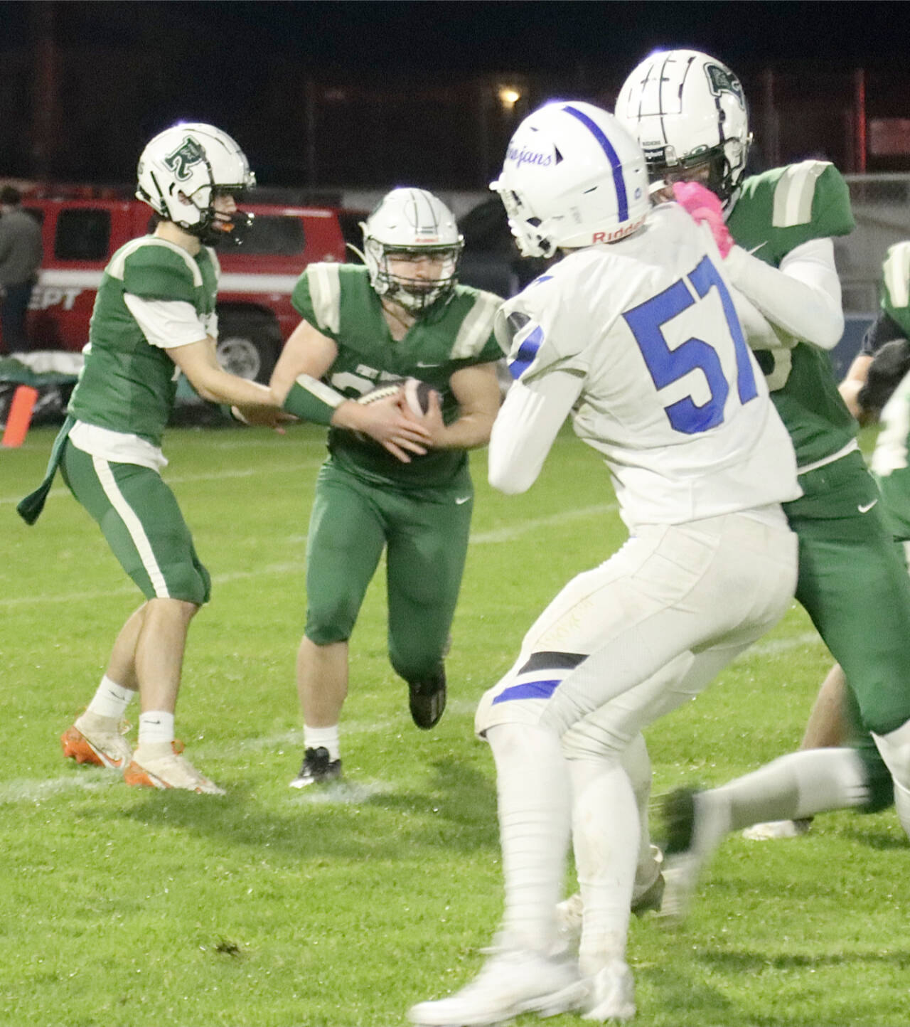 Port Angeles quarterback Blake Sohlberg hands off to running back Dylan Mann on Friday night at Port Angeles Civic Field against Olympic. (Dave Logan/for Peninsula Daily News)