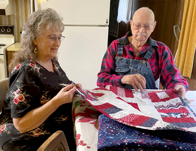 World War II veteran Arthur Bradow, right, and his daughter Barbara Cason admire a quilt sewn by his niece for his 100th birthday on Dec. 13. Bradow served in the Merchant Marine in the Pacific Theater of Operations and stateside in the U.S. Army Air Forces. (Paula Hunt/Peninsula Daily News)