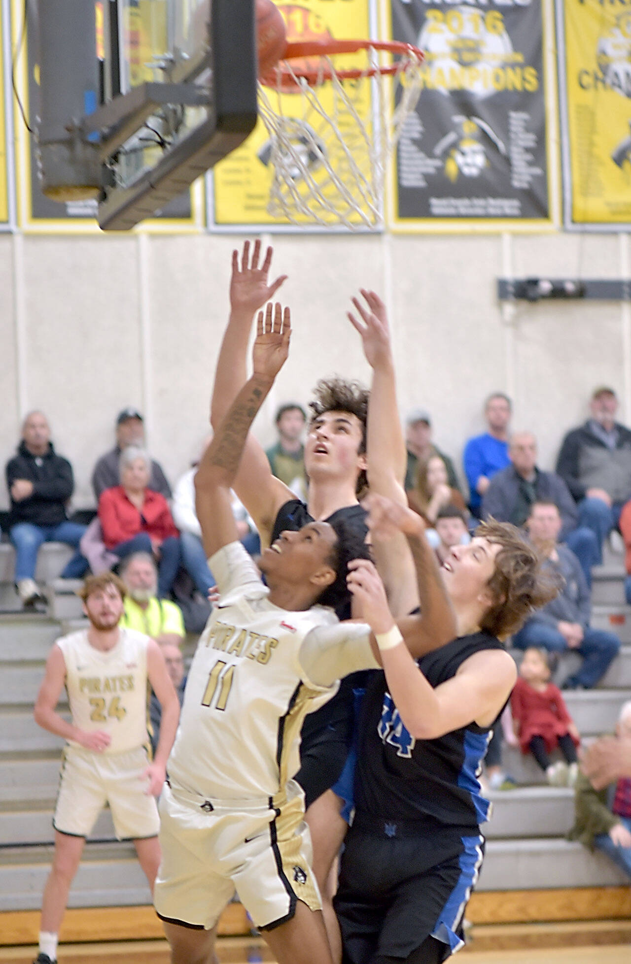 Peninsula’s Antonio Odum, front, and Edmonds’ Jack Sims and Jaden Messer, right, watch as a ball gets wedged between the rim and the backboard, forcing a jump ball on Saturday in Port Angeles. (KEITH THORPE/PENINSULA DAILY NEWS)