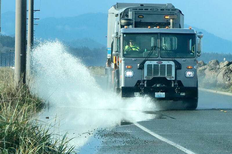 With standing water over the roads this time of year, big splashes from puddles is expected. This garbage truck heading out on Ediz Hook on Wednesday unleashes a large spray from a big puddle on the road. (Dave Logan/for Peninsula Daily News)