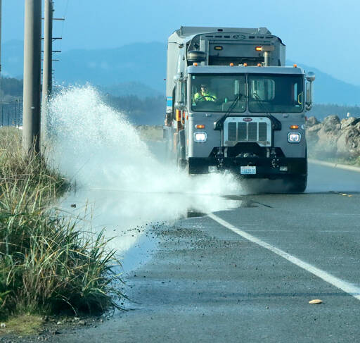 With standing water over the roads this time of year, big splashes from puddles is expected. This garbage truck heading out on Ediz Hook on Wednesday unleashes a large spray from a big puddle on the road. (Dave Logan/for Peninsula Daily News)