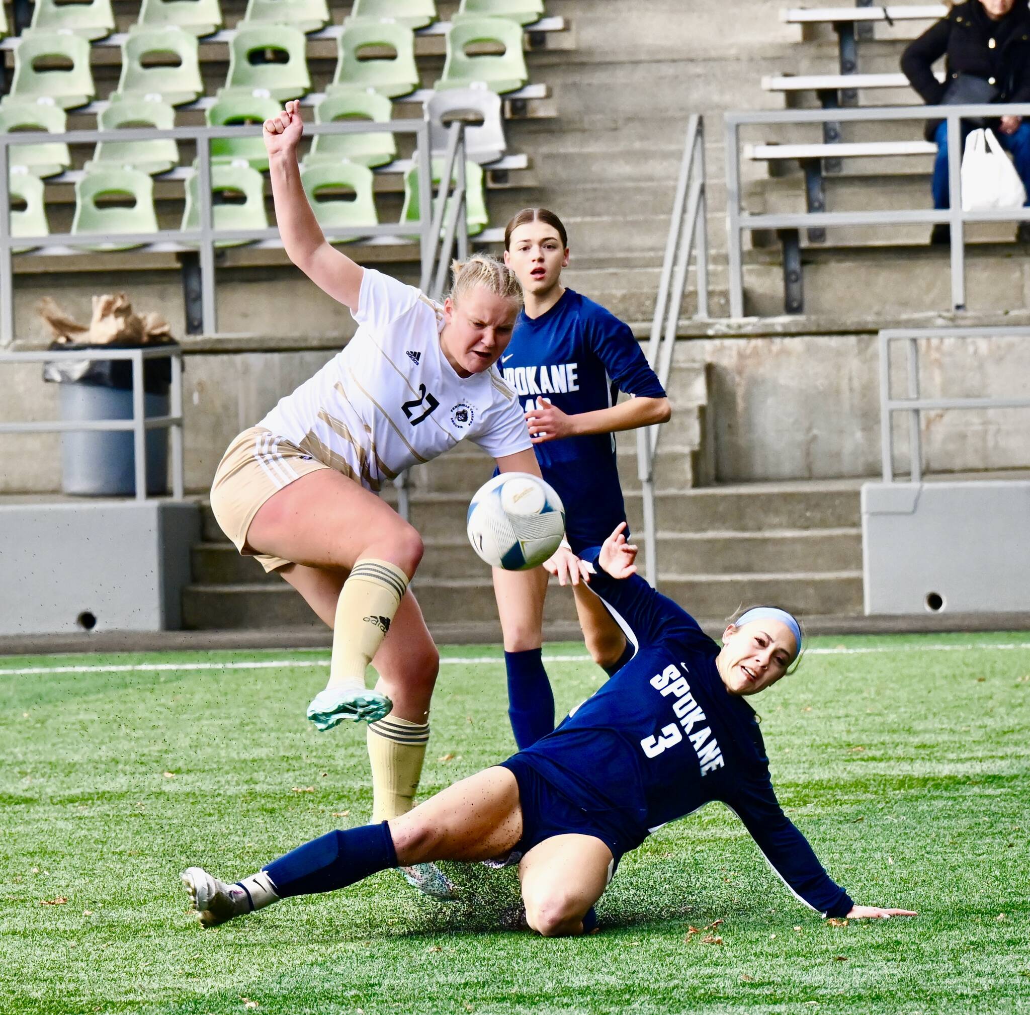 Peninsula’s Lauren Lases follows through with the kick while Spokane’s Chloe Bond attempts the slide tackle during the Pirates NWAC Semifinal victory over the Sasquatch at Starfire Sports Complex.