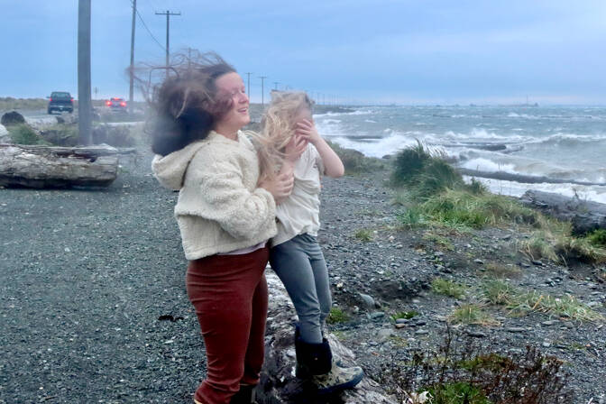 Shay-Lyn Szczepanik and her daughter Raelynn, 5, of Port Angeles are wind blown as they try to watch the wild waves at the base of Ediz Hook on Tuesday as the storm approaches. Many other weather watchers went to the spit to see and feel the winds. (Dave Logan/for Peninsula Daily News)