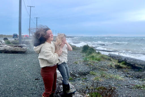 Shay-Lyn Szczepanik and her daughter Raelynn, 5, of Port Angeles are wind blown as they try to watch the wild waves at the base of Ediz Hook on Tuesday as the storm approaches. Many other weather watchers went to the spit to see and feel the winds. (Dave Logan/for Peninsula Daily News)