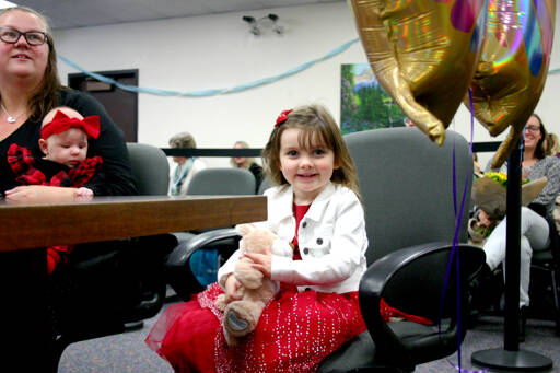 Ella Biss, 4, sits next to her adoptive mother, Alexis Biss, as they wait in Clallam County Family Court on Thursday for the commencement of the ceremony that will formalize the adoption of Ella and her 9-year-old brother John. (Emma Maple/Peninsula Daily News)