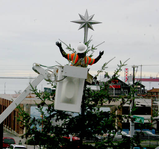 A Port Angeles city worker places a tree topper on the city’s Christmas tree, located at the Conrad Dyar Memorial Fountain at the intersection of Laurel and First streets. A holiday street party is scheduled to take place in downtown Port Angeles from noon to 7 p.m. Nov. 30 with the tree lighting scheduled for about 5 p.m. (Emma Maple/Peninsula Daily News)