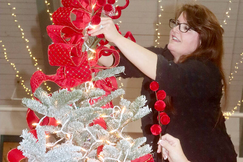 Tamara Clinger decorates a tree with the theme of “Frosted Cranberries” on Monday at the Vern Burton Community Center in Port Angeles. The helping hand is Margie Logerwell. More than three dozen trees will be available for viewing during the 34th annual Festival of Trees event this weekend. Tickets are available at www.omhf.org. (Dave Logan/for Peninsula Daily News)