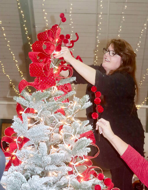 Tamara Clinger decorates a tree with the theme of “Frosted Cranberries” on Monday at the Vern Burton Community Center in Port Angeles. The helping hand is Margie Logerwell. More than three dozen trees will be available for viewing during the 34th annual Festival of Trees event this weekend. Tickets are available at www.omhf.org. (Dave Logan/for Peninsula Daily News)