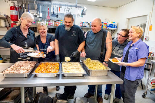 Serving up a Thanksgiving meal are, from left, Taylor Hale, Gina Landon, Shawn Lammers, Ryan Lammers, Sara Taylor and Jean Ball, all volunteers with Holiday Meals, located in the Tri-Area neighborhoods of Chimacum, Port Hadlock and Irondale. The group expected to serve up to 460 full Thanksgiving dinners with 287 being picked up, 118 delivered and 55 eaten at the Tri-Area Community Center. (Steve Mullensky/for Peninsula Daily News)