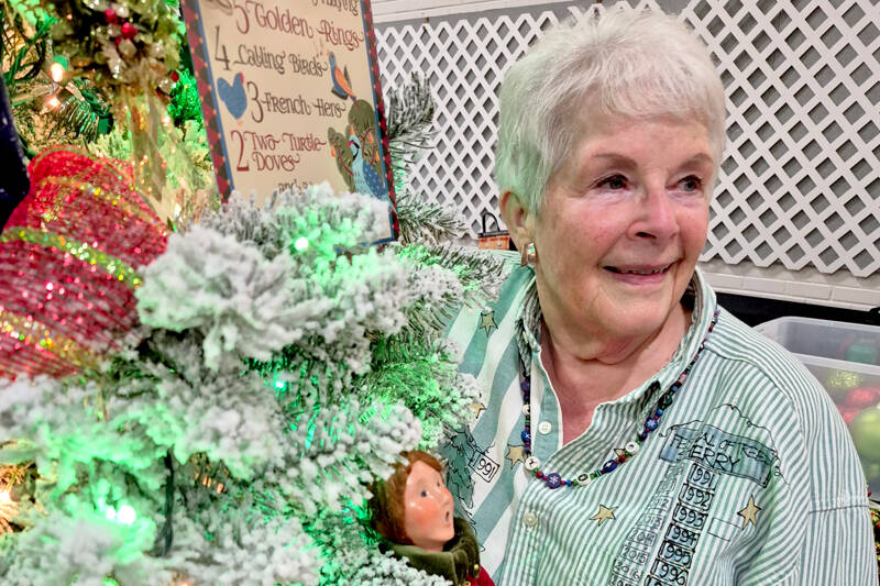 Sherry Phillips, chair of the Festival of Trees design committee, stands next to the tree Twelve Days of Christmas, which she designed personally. (Leah Leach/for Peninsula Daily News)