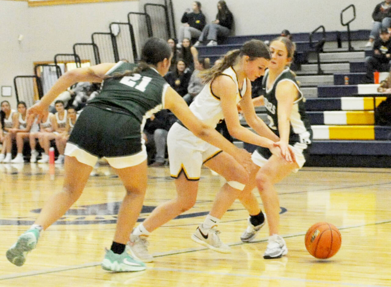 Forks’ Karee Neel drives through Roughrider defenders Sariah Doherty (21) and Becca Manson Tuesday night in Forks. Port Angeles won 44-26 in the season openers for both teams. (Lonnie Archibald/for Peninsula Daily News)