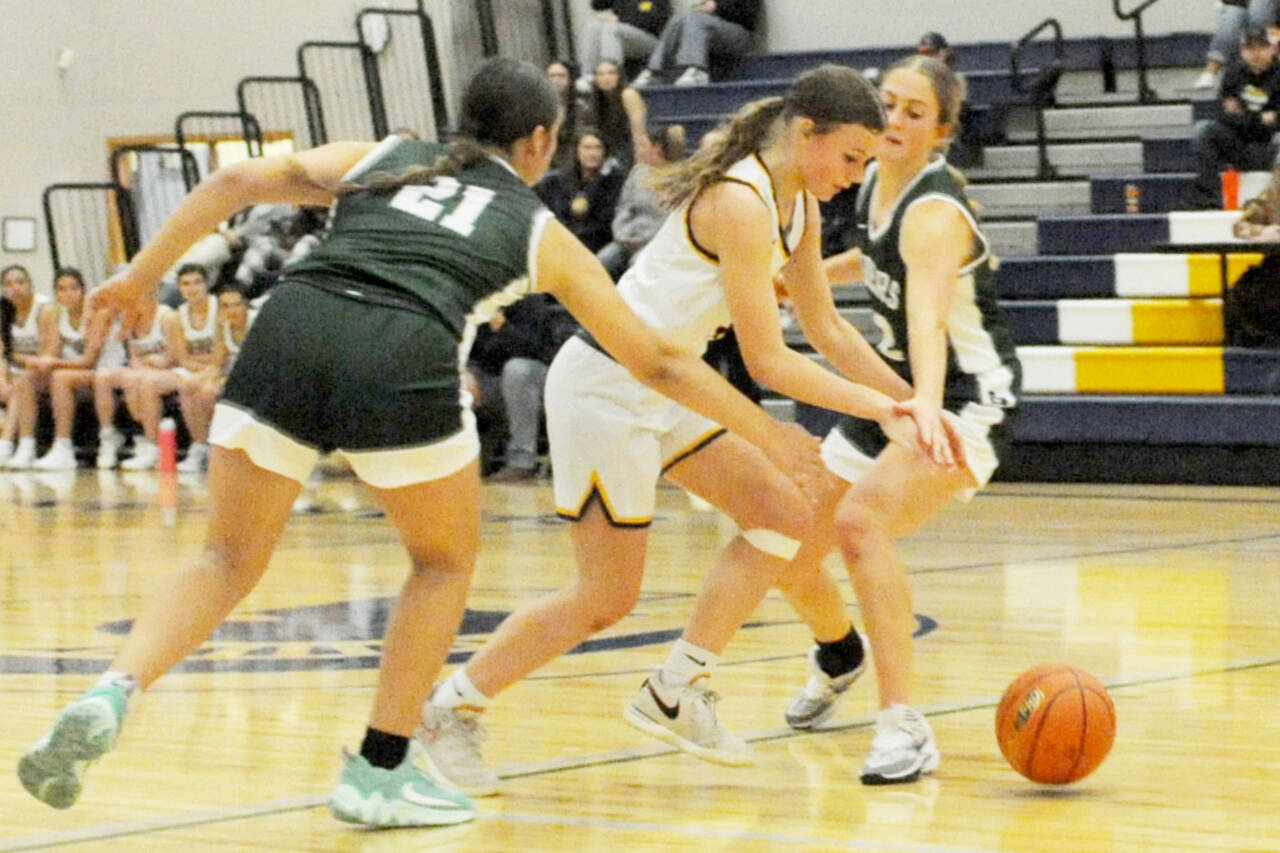 Forks' Karee Neel drives through Roughrider defenders Sariah Doherty (21) and Becca Manson Tuesday night in Forks. Port Angeles won 44-26 in the season openers for both teams. (Lonnie Archibald/for Peninsula Daily News)