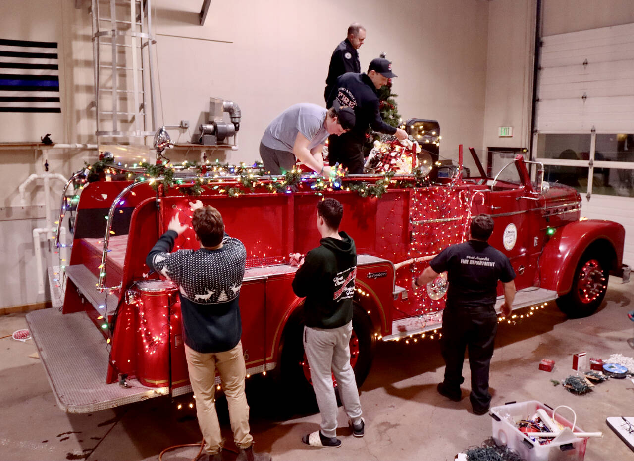 Santa’s elves, better known as the Port Angeles Fire Department, decorate their vintage 1956 Seagrave fire engine to get ready for the six-day Operation Candy Cane. This will be the 39th annual trek through the streets of Port Angeles to collect donations for area food banks. (Dave Logan/for Peninsula Daily News)