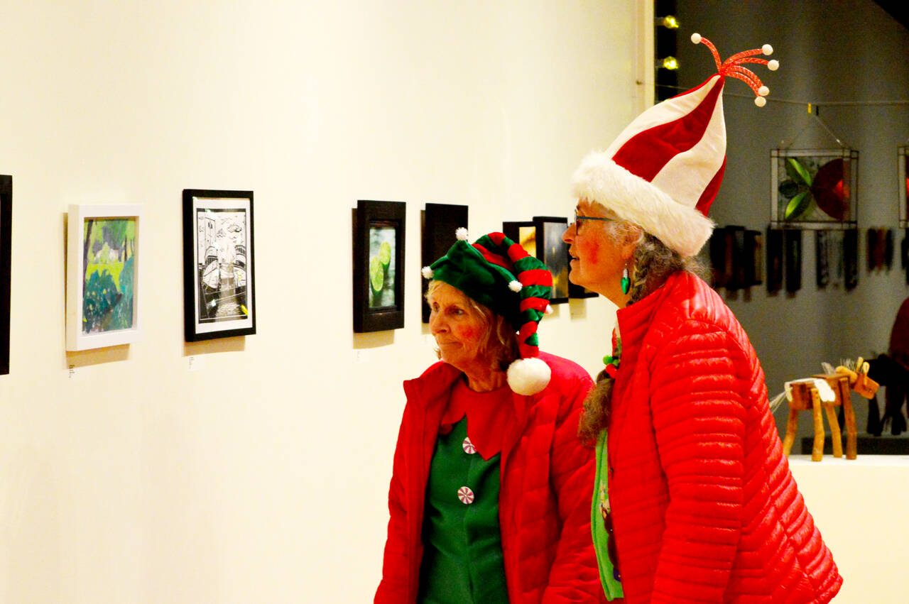 Candy cane bearers Barbra Johannsen, left, and Nancy Elder visit Northwind Art’s Jeanette Best Gallery in Port Townsend. They had helped escort Santa Claus to the tree lighting on Saturday and then decided to partake in the First Saturday Art Walk. (Diane Urbani de la Paz/for Peninsula Daily News)