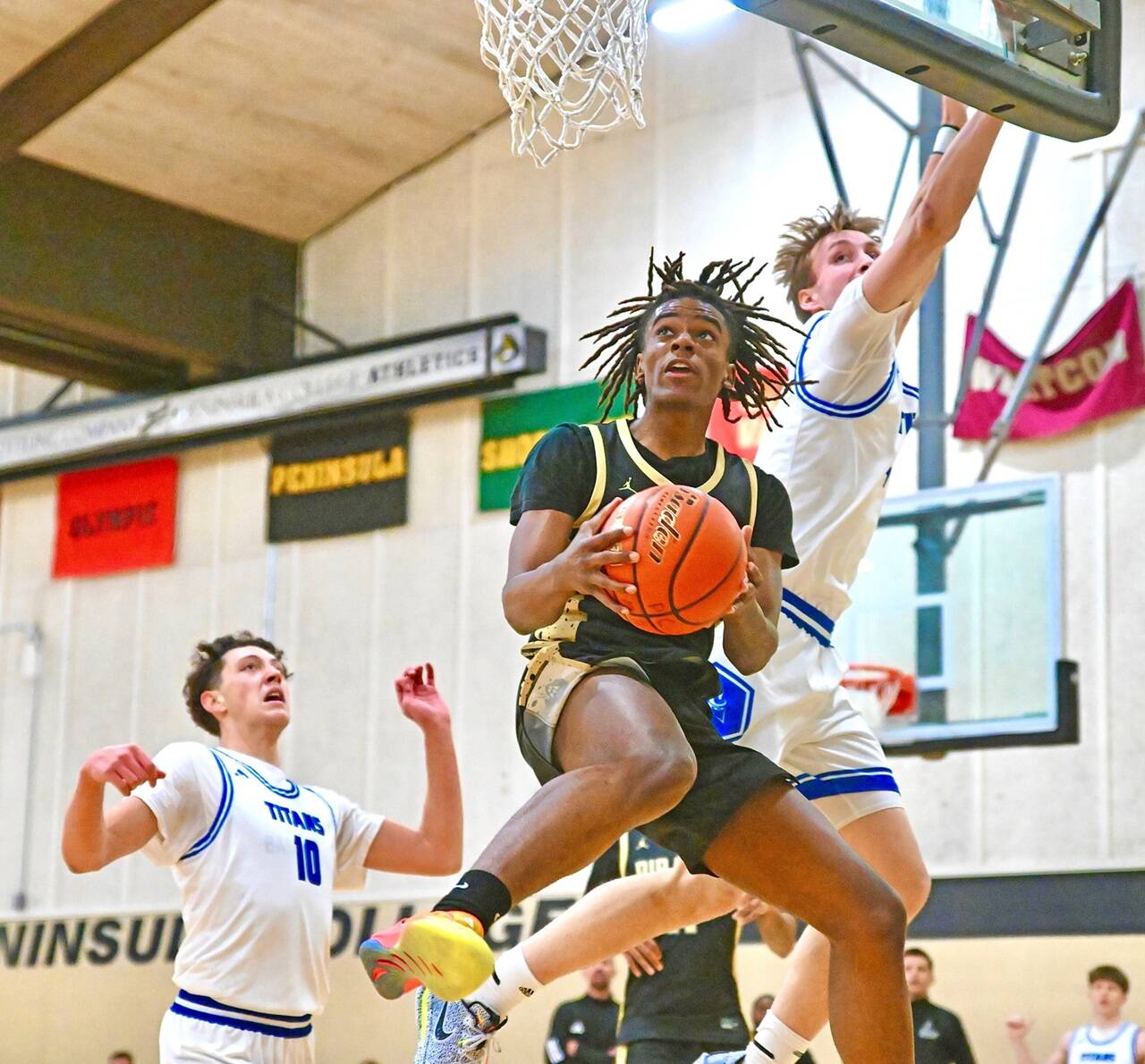 Peninsula College’s Akeem Sulaiman drives to the hoop Saturday in Port Angeles against Silas Wright (10) and Ben Thornbrue of Lane.Sulaiman scored 20 to go with 12 rebounds. (Jay Cline/Peninsula College)