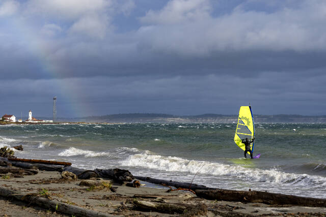 A kite-boarder takes his board into the storm-tossed waters of Port Townsend Bay at Fort Worden State Park during a sunbreak on Saturday, while a rainbow forms over the Point Wilson Lighthouse. Steve Mullensky/for Peninsula Daily News)