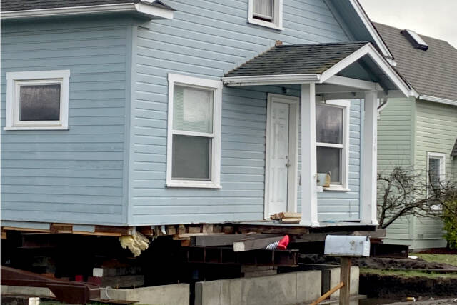 Striped legs with ruby slippers peek out from under a house being prepared to move from a lot on Third Street in Port Angeles. (Kelley Lane/Peninsula Daily News)