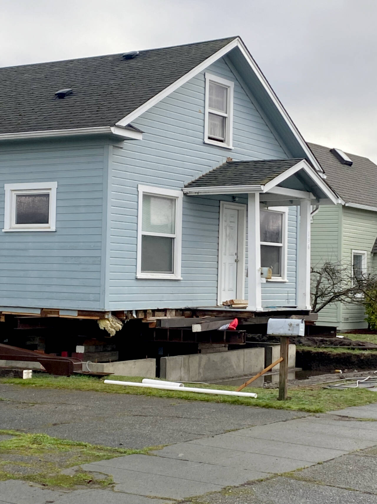 Striped legs with ruby slippers peek out from under a house being prepared to move from a lot on Third Street in Port Angeles. (Kelley Lane/Peninsula Daily News)