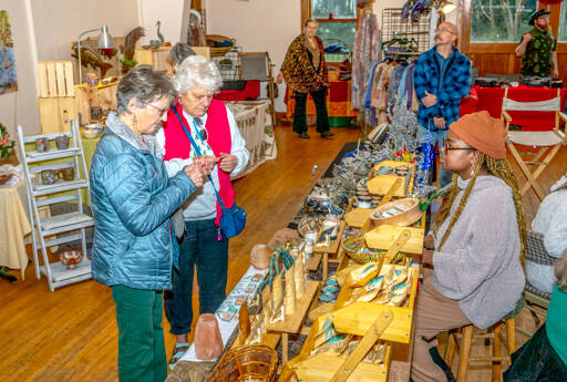 Judy Davidson, left, and Kathy Thomas, both of Port Townsend, look over the skin care products offered by Shandi Motsi of Port Townsend, one of the 20 vendors at the second annual Procrastinators Craft Fair at the Palindrome/Eaglemount Cidery on Friday. (Steve Mullensky/for Peninsula Daily News)