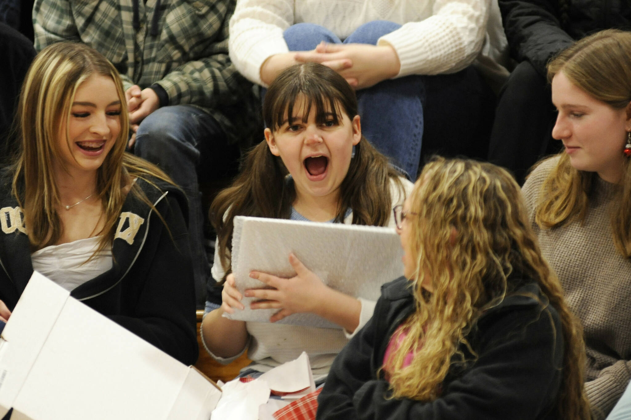 Sequim High School senior Sophia Treece shares her excitement with friends after she receives a new laptop for college at the Winter Wishes assembly on Dec. 18. (Matthew Nash/Olympic Peninsula News Group)