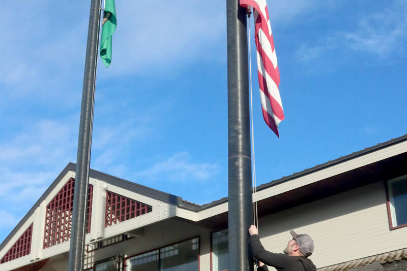 Todd Shay of the Port Angeles Parks and Recreation Department lowers the flags in front of City Hall on Monday to honor Jimmy Carter, the 39th president of the United States who died Sunday at the age of 100. The flags will stay at half-staff until the end of the day Jan. 28 by order of the governor. (Dave Logan/for Peninsula Daily News)