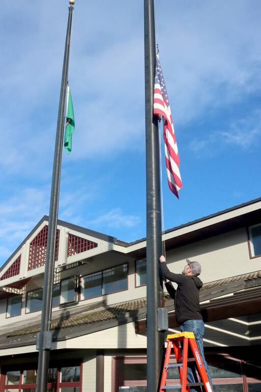 Todd Shay of the Port Angeles Parks and Recreation Department lowers the flags in front of City Hall on Monday to honor Jimmy Carter, the 39th president of the United States who died Sunday at the age of 100. The flags will stay at half-staff until the end of the day Jan. 28 by order of the governor. (Dave Logan/for Peninsula Daily News)