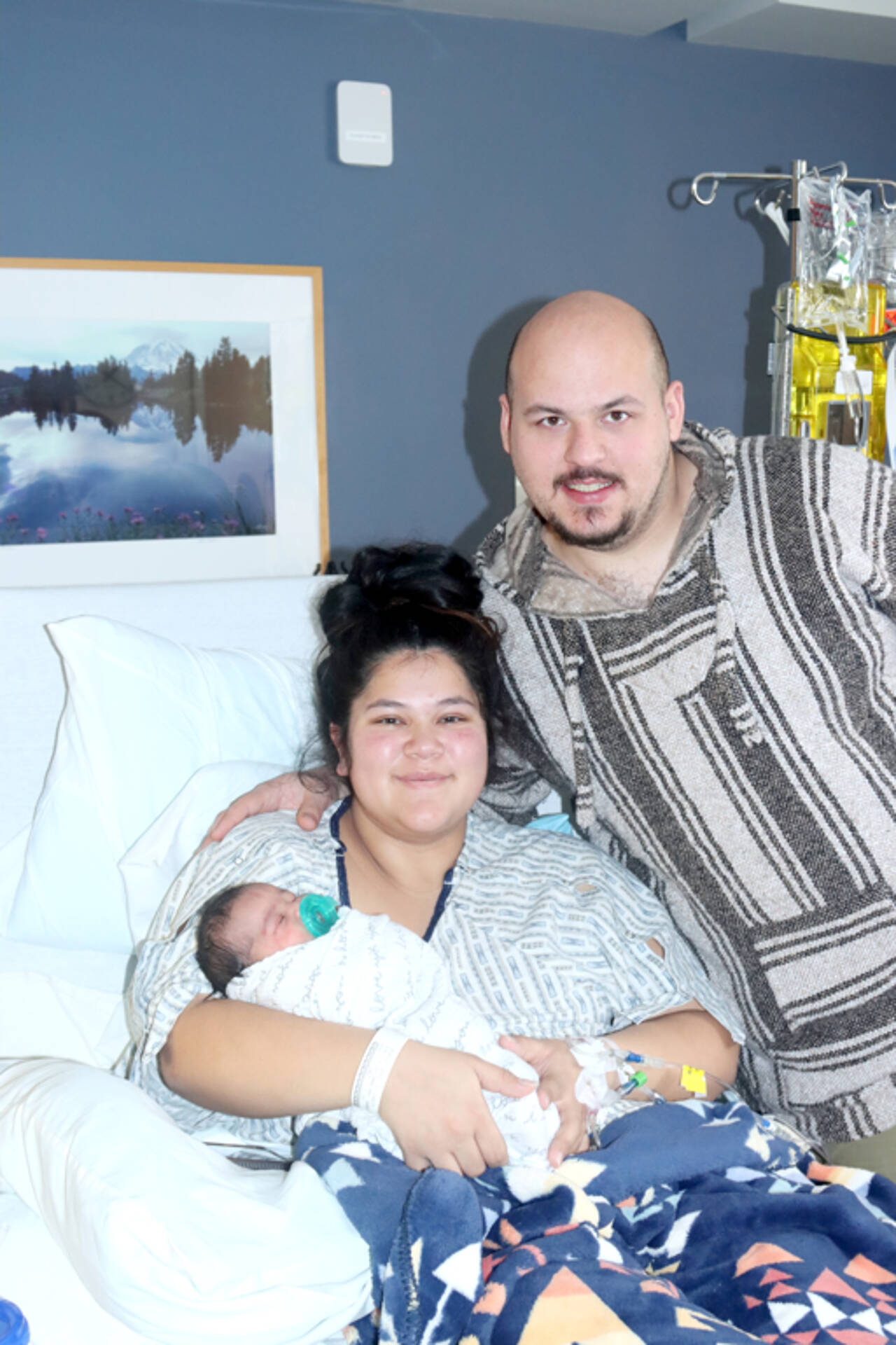 Angel Beadle holds Phoebe Homan, the first baby born on the North Olympic Peninsula in 2025. Father David Homan stands by their side in a room at Olympic Medical Center in Port Angeles. (Dave Logan/for Peninsula Daily News)