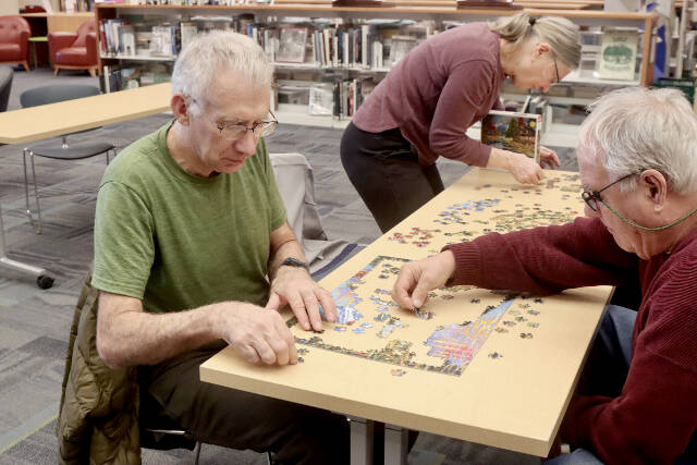 Tim Branham, left, his wife Mickey and Bill Pearl work on a 500-piece jigsaw puzzle entitled “Days to Remember.” The North Olympic Library at its main branch on South Peabody Street in Port Angeles sponsored a jigsaw puzzle contest on Saturday, and 15 contestants challenged their skills. With teams of two to four, contestants try to put together a puzzle in a two-hour time limit. Justin Senter and Rachel Cook finished their puzzle in 54 minutes to win the event. The record from past years is less than 40 minutes. The next puzzle contest will be at 10 a.m. Feb. 8. (Dave Logan/for Peninsula Daily News)