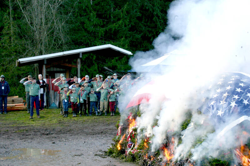 Members of Trail Life USA, a boys Christian adventure organization, salute the burning retired flags and holiday wreaths from veterans’ graves. This joint flag retirement and wreath burning ceremony took place Saturday at the Bekkevar farm in Blyn. (Emma Maple/Peninsula Daily News)