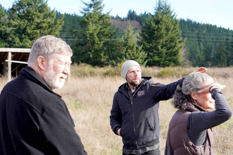 Gesturing toward the Olympic Mountains, Erik Kingfisher of Jefferson Land Trust leads a site tour with project architect Richard Berg and Olympic Housing Trust board trustee Kristina Stimson. (Olympic Housing Trust)