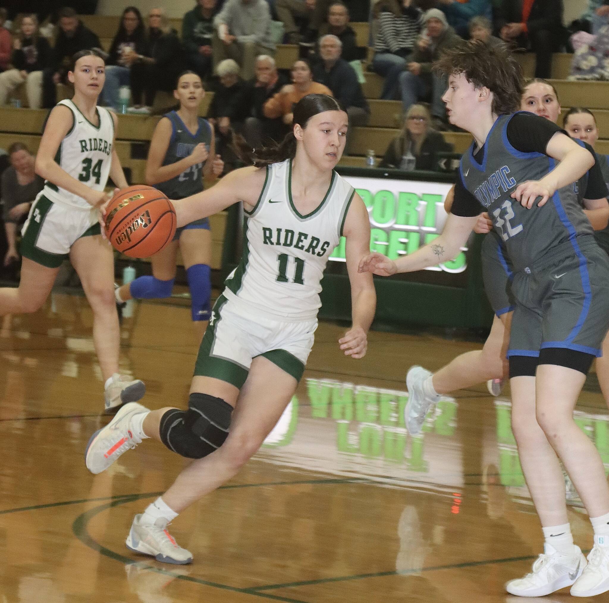 Dave Logan/for Peninsula Daily News Port Angeles’ Lindsay Smith drives to the basket and tries to get past Olympic’s Gabi McCoy during the Roughriders’ win over the Trojans on Friday.