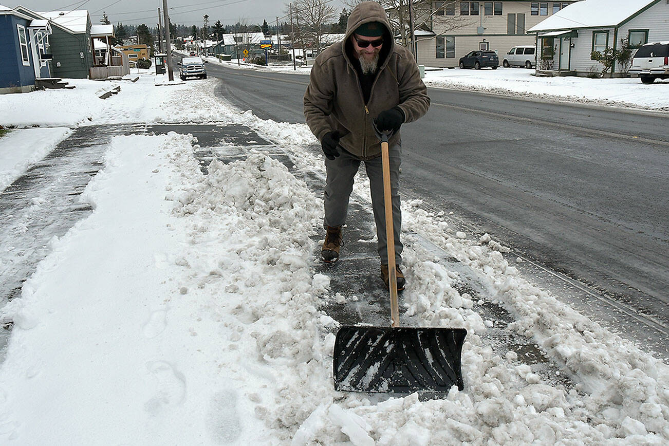 Eric Spencer, a landscaping and janitorial worker for New Life Open Bible Church, clears snow from a sidewalk next to the church at Sixth and Peabody streets in Port Angeles on Thursday morning. (Keith Thorpe/Peninsula Daily News)