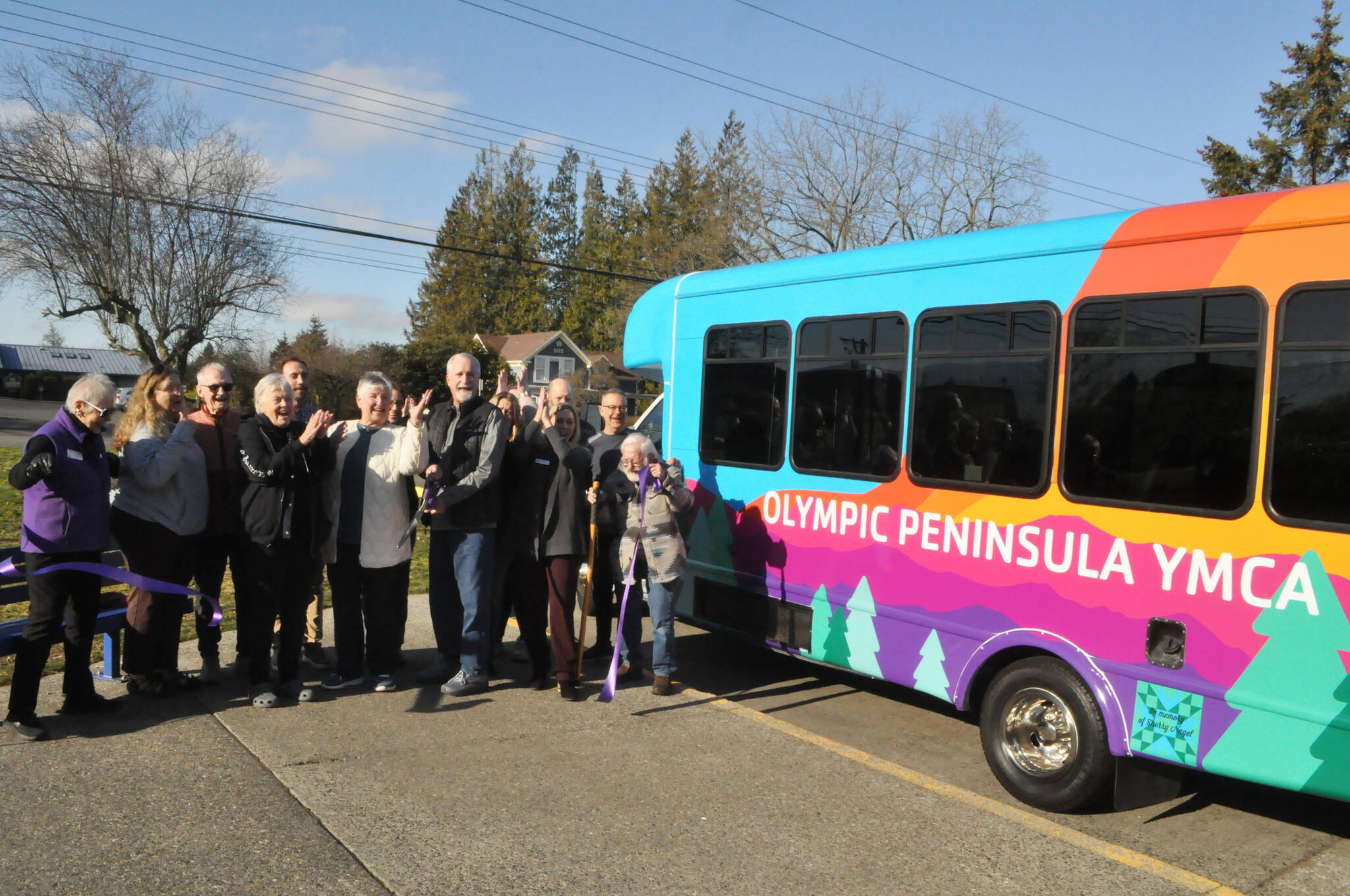 Mike Speer of Bonney Lake, the brother of Sherry Nagel, a former board member of the YMCA of the Olympic Peninsula, cuts a ceremonial ribbon on Jan. 28 courtesy of the Sequim-Dungeness Valley Chamber of Commerce to commemorate a new bus that Nagel’s estate helped fund. The bus is dedicated in Nagel’s honor. (Matthew Nash/Olympic Peninsula News Group)