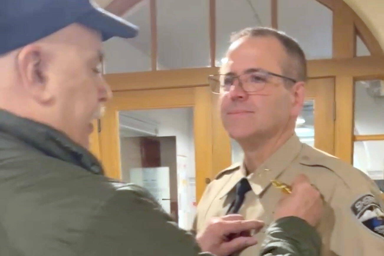 Retired Sheriff Joe Nole pinning interim Sheriff Andy Pernsteiners new badge on, following his appointment at the Jefferson County Courthouse.