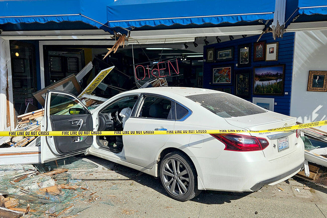 Port Angeles police officers and firefighters responded Friday after a car when into a building in the 600 block of East Front Street. Traffic was disrupted until the vehicle could be cleared from the scene, police said. (Port Angeles Police Department)