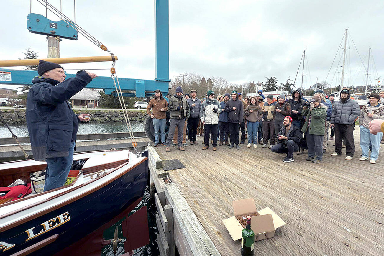 Chuck Hancock of Tacoma raises a glass to toast the launching of his boat, Diana Lee, named after his wife, which was built by the students of the Northwest School of Wooden Boat Building in Port Hadlock. The boat is a 24-foot one-off design by designer Jonathan Madison of Lummi Island and was trailered in and launched from the travel lift at Point Hudson Marina on Friday morning. (Steve Mullensky/for Peninsula Daily News)