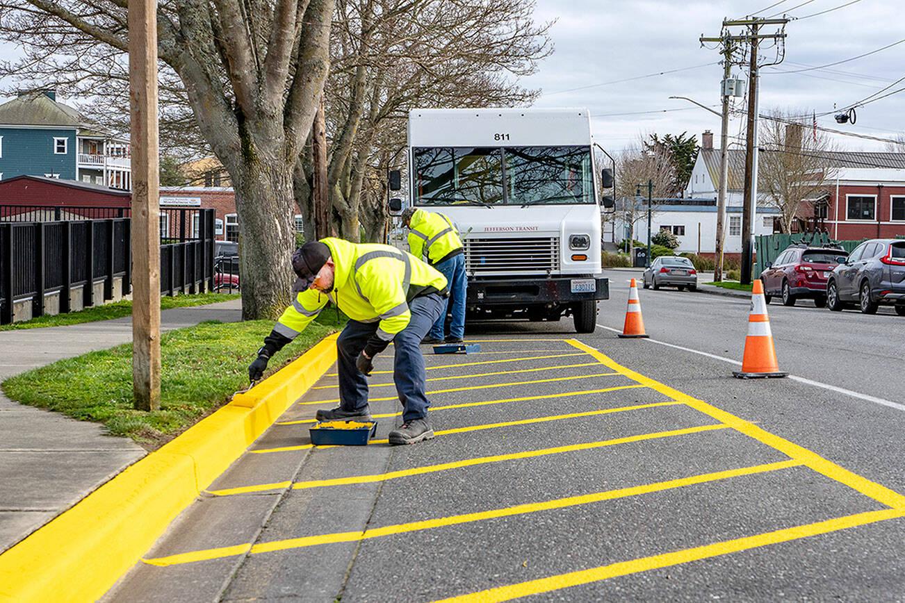 Workers from Jefferson Transit repaint the bus stop parking area at the corner of Madison and Jefferson streets in Port Townsend on Friday. The yellow paint was purchased from a local hardware store. (Steve Mullensky/for Peninsula Daily News)